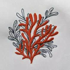 a close up of a red coral embroidered onto a white shirt with blue and orange thread