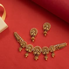 Description: Shauri is a short necklace made to reflect the rich heritage of India's glorious past. Handcrafted in antique gold, this bold necklace features traditional Indian floral motifs and semi-precious CZ stones. A jewelry design that is as stately as it is striking! Details & Specifications:Materials used: Brass Alloy with Antique Gold platingWeight –Necklace - 32 gm, Earring - 11 gmLength –Necklace - 9 cm, Earring-3.5 cmMake it customWant to make it a custom necklace? Sure! Reach out to Kolkata Gold Jewellery Design, Gold Necklace Indian Bridal Jewelry Simple, Gold Necklace Set Antique, Traditional Jewelry Antique, Gold Necklace Set Design, Indian Floral Motifs, Stones Necklace Gold, Fancy Necklaces, Short Gold Necklace