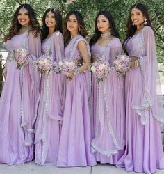 a group of women standing next to each other wearing purple dresses and holding bouquets