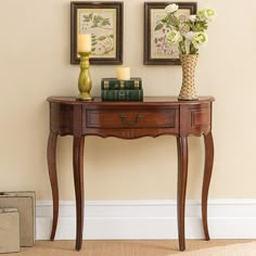 a wooden table with two vases on top of it next to a lamp and flowers