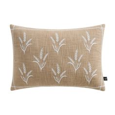 a beige pillow with white embroidered leaves on the front and back, sitting on a white background