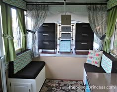 the interior of a camper with green drapes and black storage bins on each side