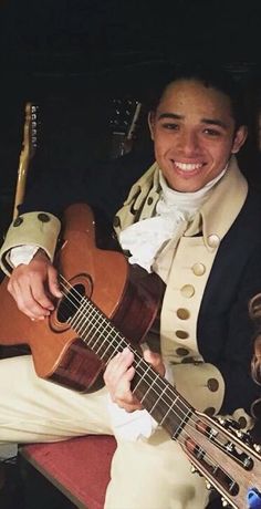 a man holding a guitar and smiling at the camera