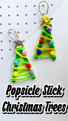 popsicle stick christmas trees with pom - poms hanging from the top and bottom