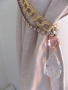 a close up of a curtain with a chain attached to it and a crystal tear hanging from the side