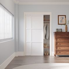 an empty bedroom with white walls and wooden furniture, including a chest of drawers in the foreground