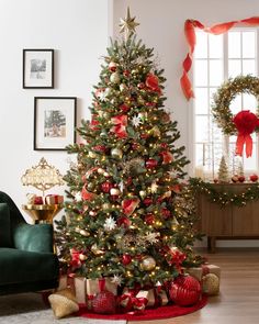 a decorated christmas tree in a living room with red and gold ornaments on the floor