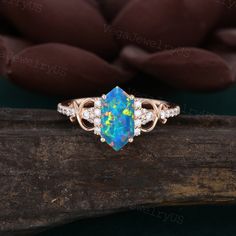 an opal and diamond ring on top of a piece of wood