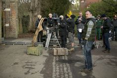 a group of people standing around each other in front of a camera set up on the street