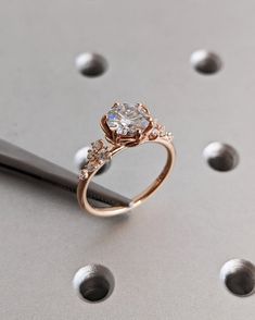 a diamond ring sitting on top of a piece of metal with holes in the background