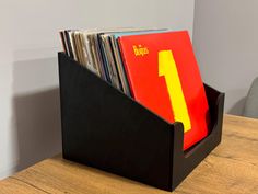 a wooden table with a black holder filled with vinyl records and folders on it