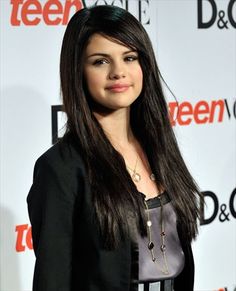 a woman with long black hair standing in front of a red carpet