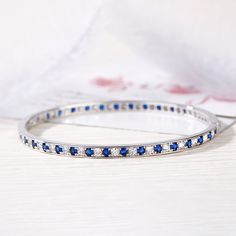 Add sophisticated style to her look with this exquisite bangle bracelet. Crafted in sterling silver, this darling design showcases blue round cut stones alternating with shimmering white round stones. Dazzling stones are always an excellent choice and she'll absolutely adore this delightful bracelet.Weight: 13.32 gWidth: 3.8 mmHeight: 2.6 mmThickness: 3.8 mmMaterial: 925 SilverStone Type: Jeulia® StonePlating Color: SilverBracelet Size: 180 mm Elegant Blue Stackable Jewelry, White Gold Gemstone Bangle Fine Jewelry, Fine Jewelry White Gold Gemstone Bangle, White Gold Gemstone Diamond Bangle Bracelet, White Gold Gemstone Bangle, White Gold Diamond Bangle Bracelet With Gemstone, Sapphire Round Bracelets For Wedding, Sterling Silver Cubic Zirconia Gemstone Bracelet, Fine Jewelry Bracelets With Sparkling Stones