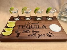 a wooden tray topped with shots and limes