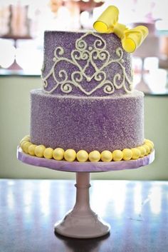 there is a purple cake with yellow candies on the top and bottom tiers