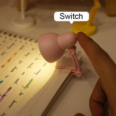 a hand is pointing at a pink light on a notepad that says switch button