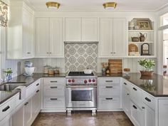 a kitchen with white cabinets and stainless steel stove top oven in the center, surrounded by brown tile flooring