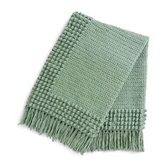 a light green blanket with fringes on the bottom and one end folded up in two rows