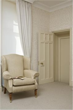 a chair sitting in the corner of a room next to a doorway with curtains on it