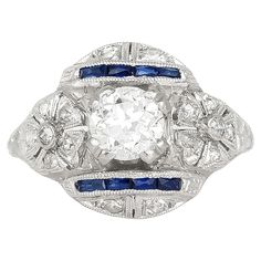 an antique style diamond and sapphire ring with blue stones in the center, on a white background