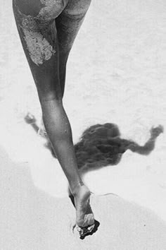 a woman in a bathing suit walking on the beach with her legs spread wide open