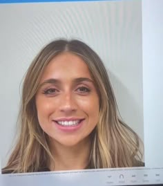 a woman smiling and looking at the camera on a computer screen with an image of her face