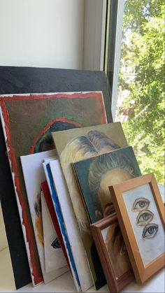 an assortment of art work displayed on a window sill