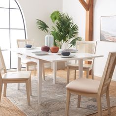 a white table with four chairs and a potted plant in the corner next to it