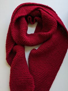 a red knitted scarf laying on top of a white table