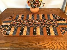 a wooden table topped with a vase filled with flowers and a quilted placemat