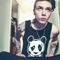 a man with tattoos on his arm wearing a panda shirt and looking at the camera