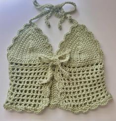 a green crocheted top with a bow on the front and back, sitting on a white surface