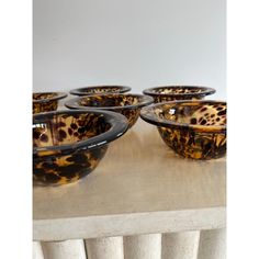 six brown and black glass bowls sitting on top of a wooden table next to a radiator