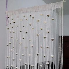 a white curtain with flowers hanging from it's side in front of a mirror