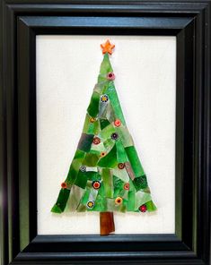 a small christmas tree made out of green plastic bottle caps in a black framed frame