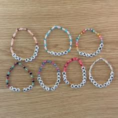 six personalized bracelets with name beads on wooden surface, including one for the child's name