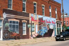 a black truck parked in front of a building with a mural on it's side