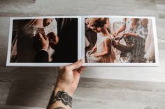 a hand holding an open photo book on top of a wooden floor