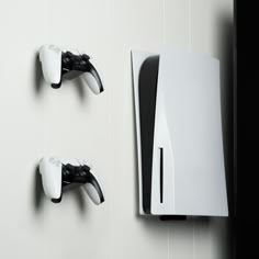 two white and black wall mounted video game controllers next to each other on the wall