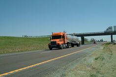 an orange tanker truck driving down the highway