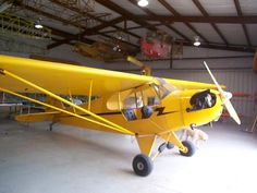 a small yellow airplane sitting inside of a hangar