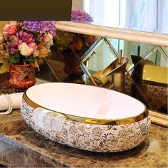 a bathroom sink with flowers on the counter and mirror in the backround behind it