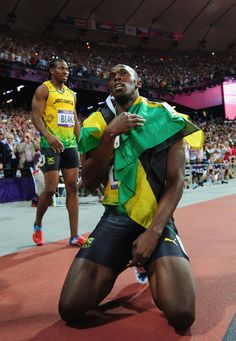 a man sitting on the ground in front of an audience at a sporting event wearing a green and yellow shirt