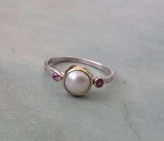 Pearl engagement ring,unique one of a kind pearl engagement ring,14k gold and sterling silver engagement ring,alternative engagement ring,pearl ring. One of a kind pearl engagement ring A beautiful fresh water pearl is set in a 14k solid yellow gold bezel on a delicate sterling silver band.a pink tourmaline is set on each side of the pearl. Genuine gemstones! Ring size is 7 u.s READY TO SHIP:) Measures: pearl diameter- 8mm tourmalines- 2 mm ring band- 1.5 mm Unique Pearl Jewelry For Anniversary, White Ruby Ring For Wedding In Sterling Silver, White Sterling Silver Ruby Ring For Wedding, Unique Sterling Silver Pearl Ring For Wedding, Sterling Silver Pearl Ring Fine Jewelry, Elegant Handmade Pearl Promise Ring, Sterling Silver Pearl Drop Ring For Promise Occasions, Sterling Silver Pearl Drop Ring For Promise, Unique Handmade Pearl Promise Ring