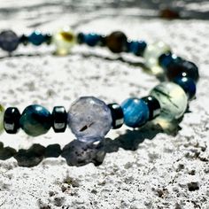 The Hematite, Kyanite, Iolite, and Prehnite crystal bracelet serves as a guiding light for intuition and grounding, a tangible representation of calm and mental clarity for the soul. By incorporating Hematite, this bracelet secures the wearer's connection to the earth, providing a stable base to expel negativity and enhance focus. Kyanite, with its vibrant blue hues, acts as a beacon of truth and alignment, inspiring the wearer to connect with their inner wisdom and communicate their truth confidently. Iolite, known as the vision stone, clears the mind's mists, offering sharpness of intuition and clarity of thought. Prehnite, a stone of quiet waters and gentle foliage, wraps the wearer in protective calm, warding off disturbances while nurturing inner peace and harmony. This bracelet is no Prehnite Crystal, Guiding Light, Inner Wisdom, Peace And Harmony, Mental Clarity, Vibrant Blue, State Of Mind, Crystal Bracelet, Blue Hues