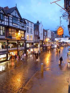 people are walking down the street at night in an area with many shops and restaurants