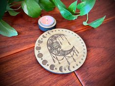 a wooden coaster sitting on top of a table next to a candle and some leaves