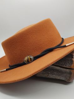 Elevate your cowboy hat style with our exquisite handcrafted hat band featuring a captivating oval Tigers Eye stone as its centerpiece. Each stone is meticulously polished to perfection, showcasing its natural beauty and warm glow. Designed to add a touch of elegance to your western look, this hat band is adorned with an oval silver-tone setting, creating a striking contrast against the rich hue of the stone. The band is crafted from black vegan cording, accented with fancy silver-tone "stacked" end caps. Hat bands are more than just accessories; they're a form of personal expression, reflecting your unique style and personality. As someone who grew up on the ranch, I understand the significance of these adornments. Adjustable to fit different hat sizes, this hat band offers versatility an Cowboy Hat Band, Look Western, Cowboy Hat Styles, Cowboy Hat Bands, Gifts Boho, Tigers Eye Stone, Chapeau Cowboy, Boho Cowgirl, Western Hat