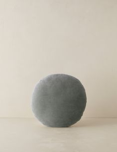 a gray round pillow sitting on top of a white table