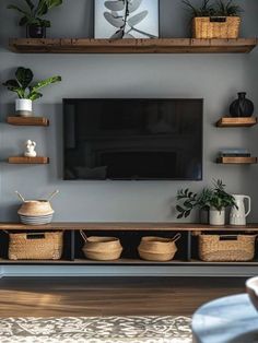 a flat screen tv mounted to the side of a wall next to baskets and potted plants